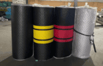 Black foam rollers with yellow, red, and gray accents, ideal for fitness and physical therapy exercises, displayed in a warehouse setting.